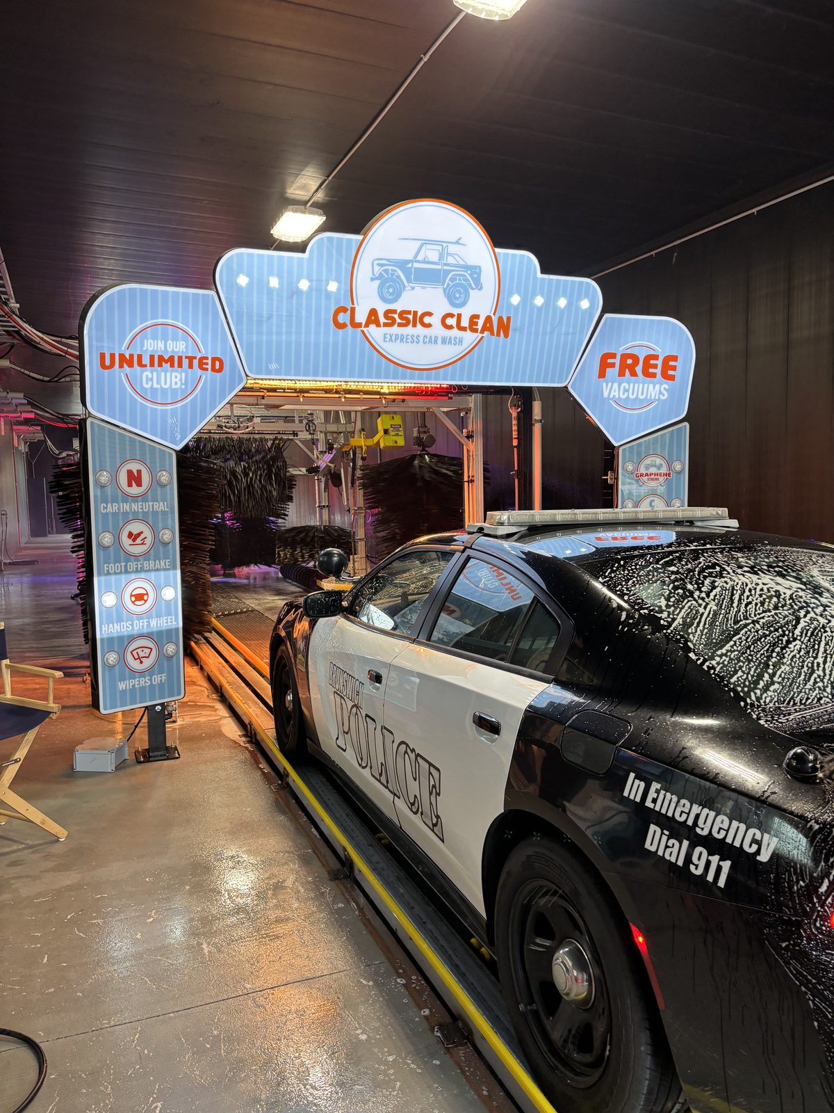 A Brunswick Police cruiser covered in foam rolling into the Classic Clean tunnel under the lit entry arch